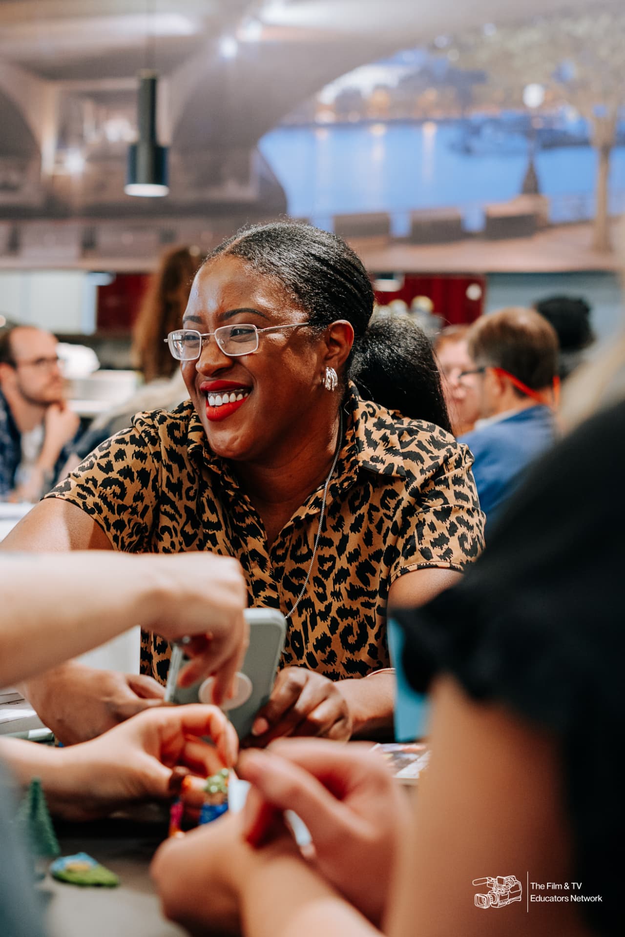 An educator laughing with colleagues at a workshop table